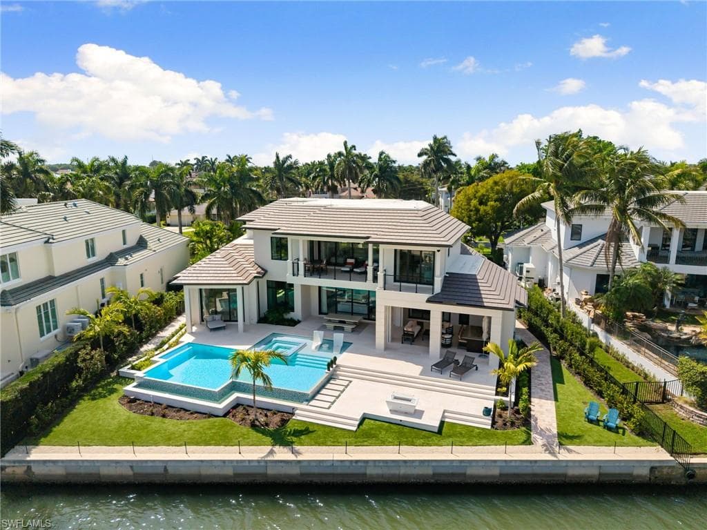 Back of house with a fenced backyard, a patio, a water view, a pool with connected hot tub, and an outdoor living / dining area