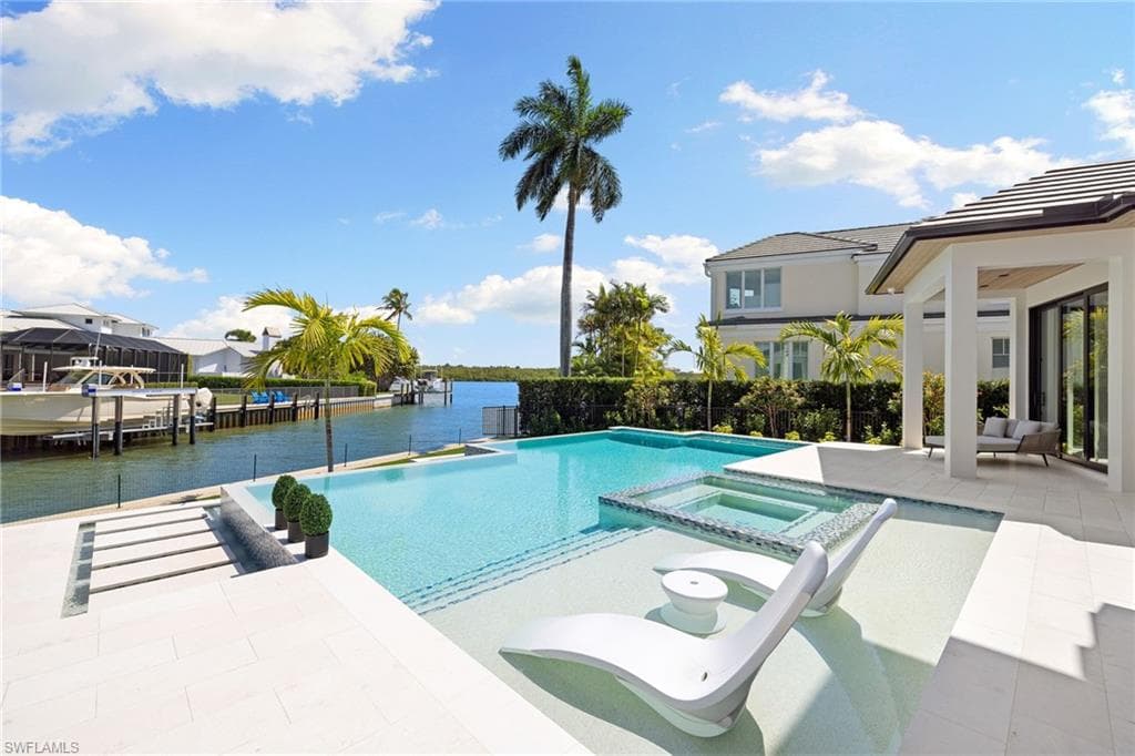 Integrated pool / spa featuring a patio, a water view, and a boat dock