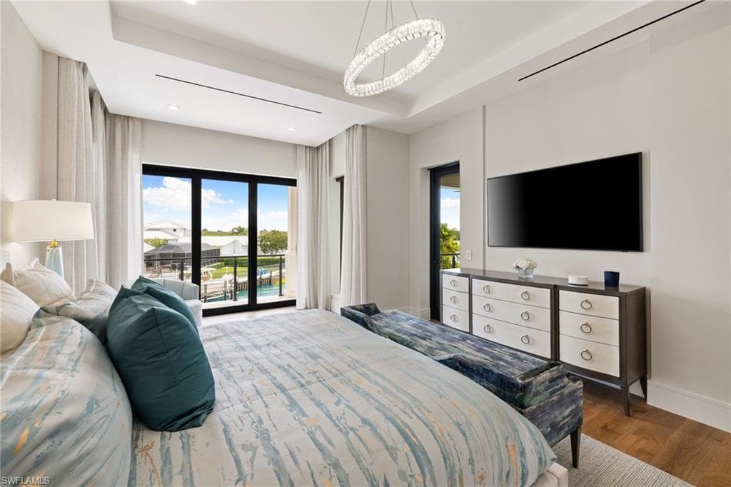 Bedroom featuring access to exterior, wood finished floors, and a raised ceiling