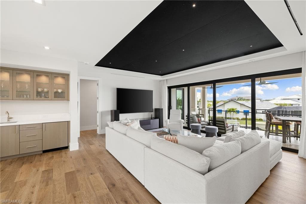 Living area with a raised ceiling and light wood-style flooring