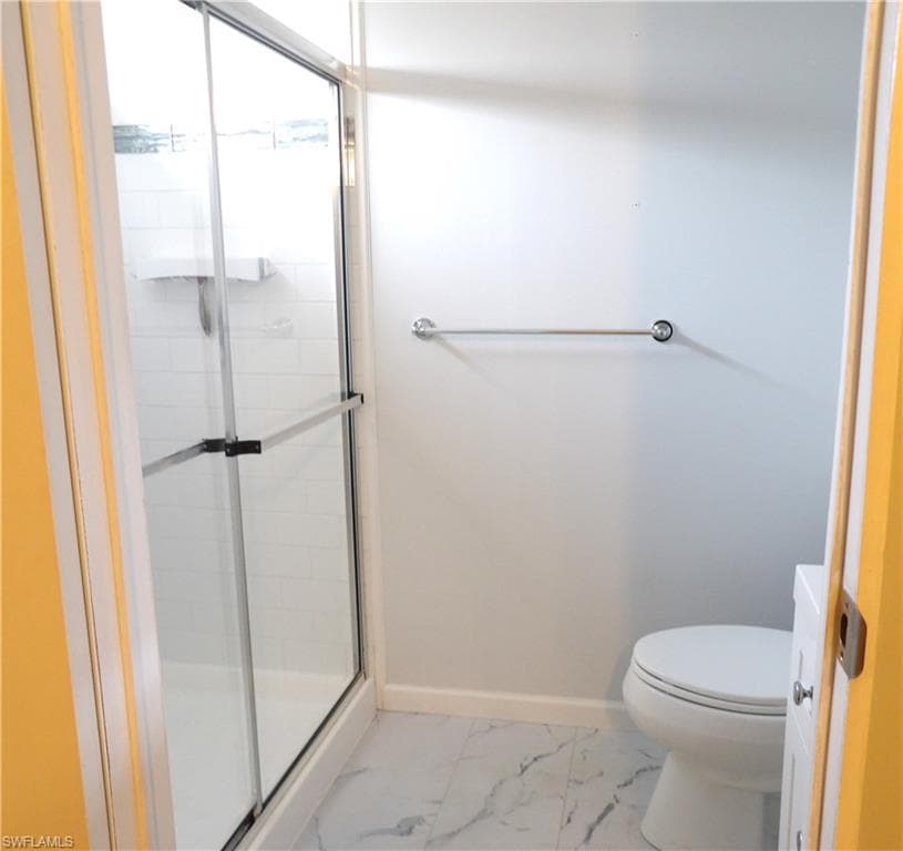 Bathroom featuring a shower stall, vanity, and light marble finish flooring