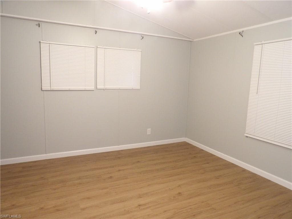 Primary room featuring vaulted ceiling and laminated floors