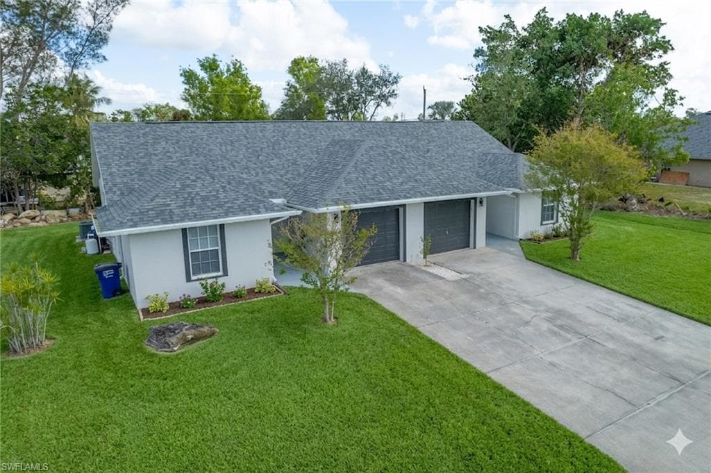 Single story home featuring a front lawn, a shingled roof, a garage, and stucco siding