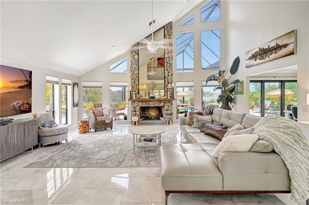 Living area featuring marble finish floor, a ceiling fan, high vaulted ceiling, and a fireplace