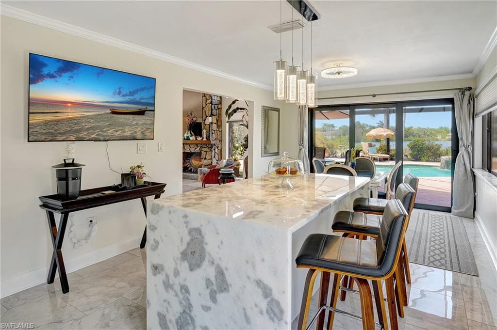 Kitchen with a breakfast bar, marble finish floor, crown molding, and light stone counters