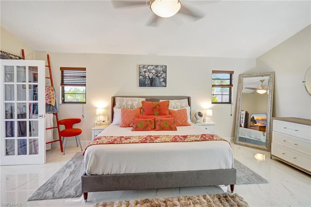 Bedroom with marble finish floor, ceiling fan, and multiple windows