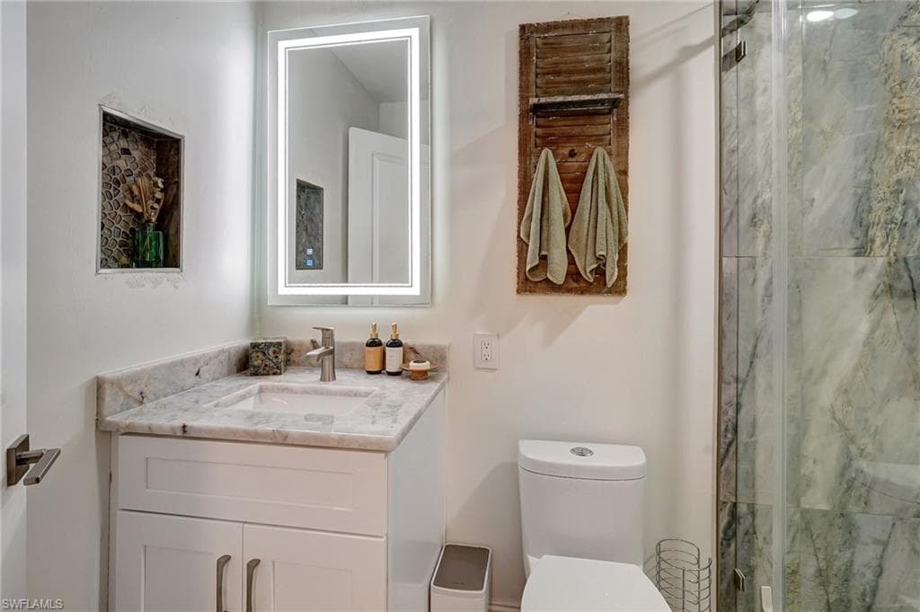 Full bath featuring toilet, vanity, and a shower stall