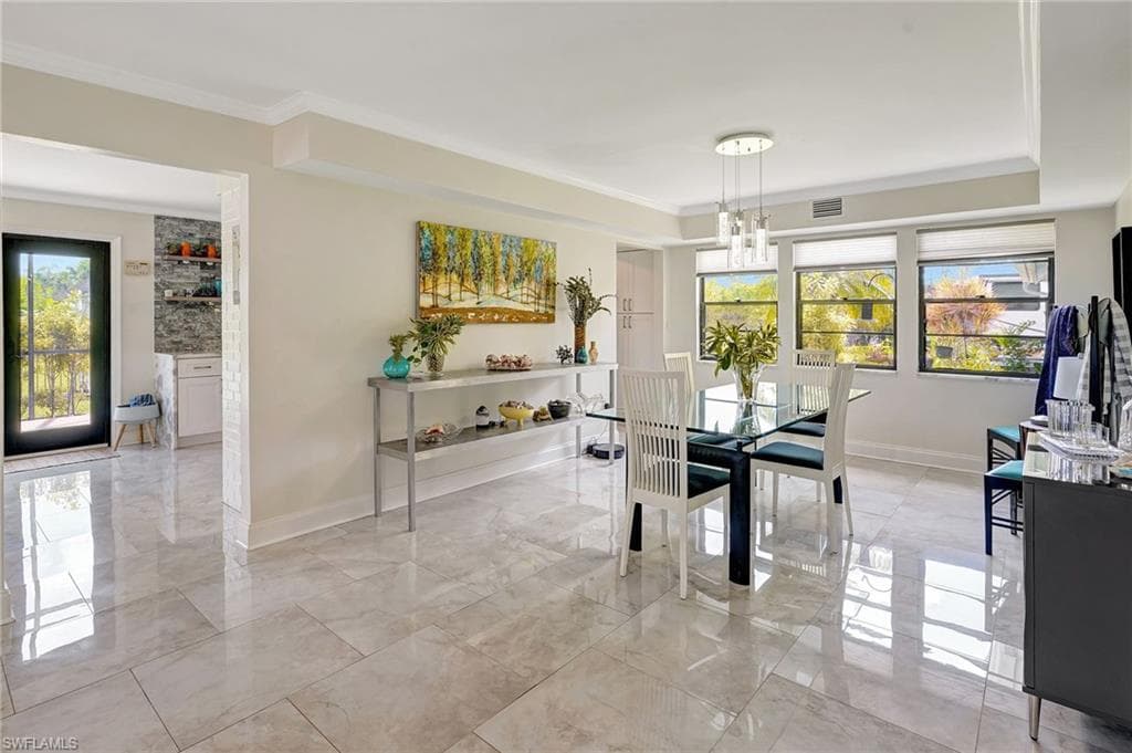 Dining area with marble finish floor and ornamental molding