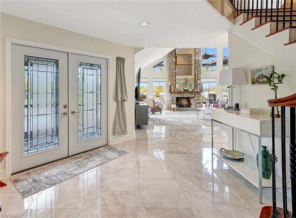 Entrance foyer with marble finish floor, ceiling fan, a high ceiling, and french doors