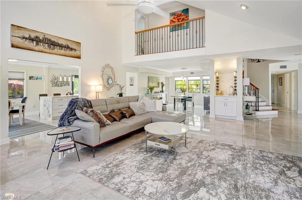 Living area featuring marble finish floor, ceiling fan, stairs, and a towering ceiling