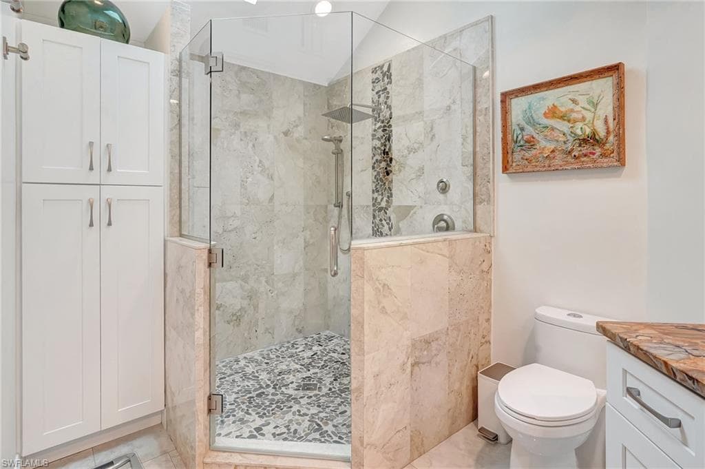 Bathroom with toilet, vanity, and a shower stall