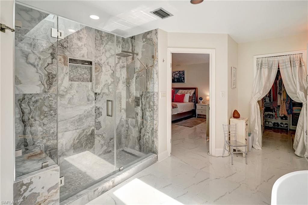 Bathroom featuring a marble finish shower, marble finish floor and ensuite bath