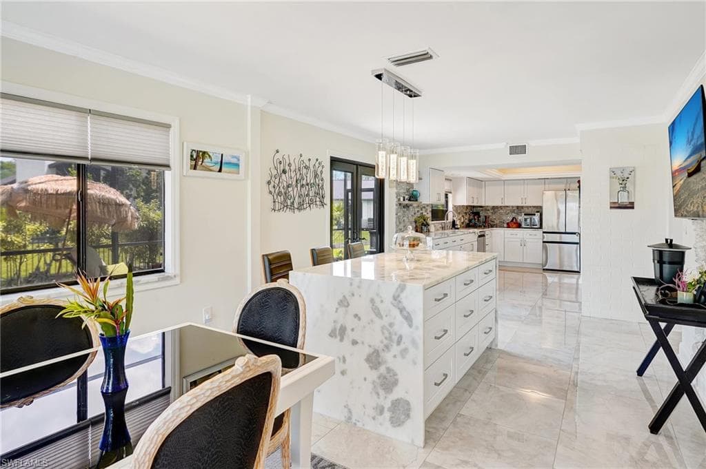 Kitchen featuring crown molding, freestanding refrigerator, marble finish floor, visible vents, and white cabinets