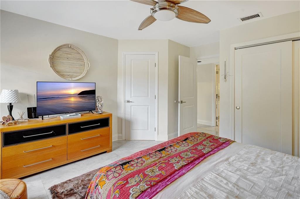 Bedroom featuring a closet, light tile patterned floors, baseboards, and ceiling fan