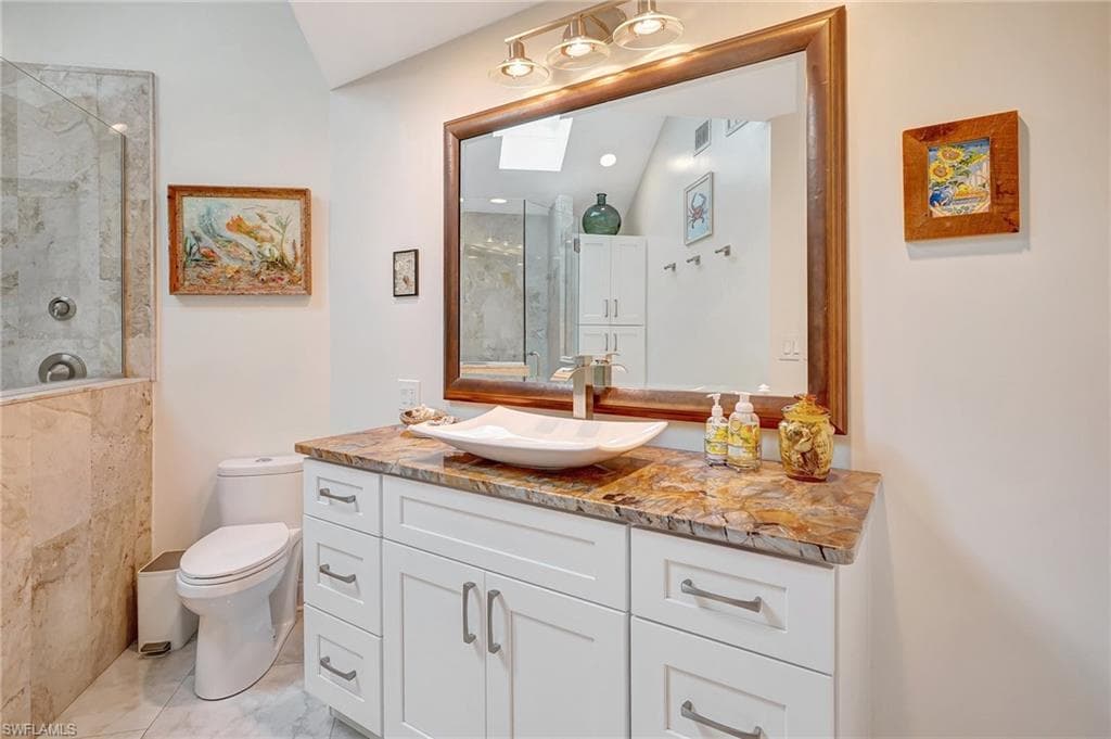Full bathroom featuring marble finish floor, toilet, vanity, and a tile shower