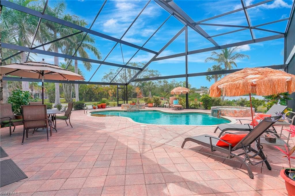 View of swimming pool with a patio, a pool with connected hot tub, and a lanai