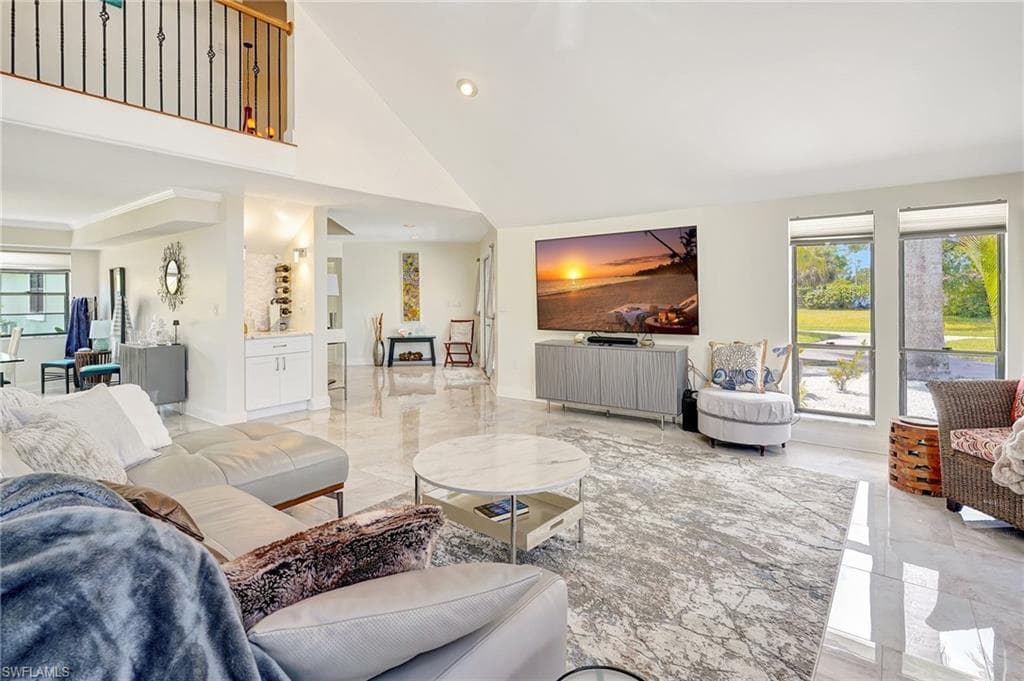 Living room with marble finish floor, a towering ceiling, and recessed lighting