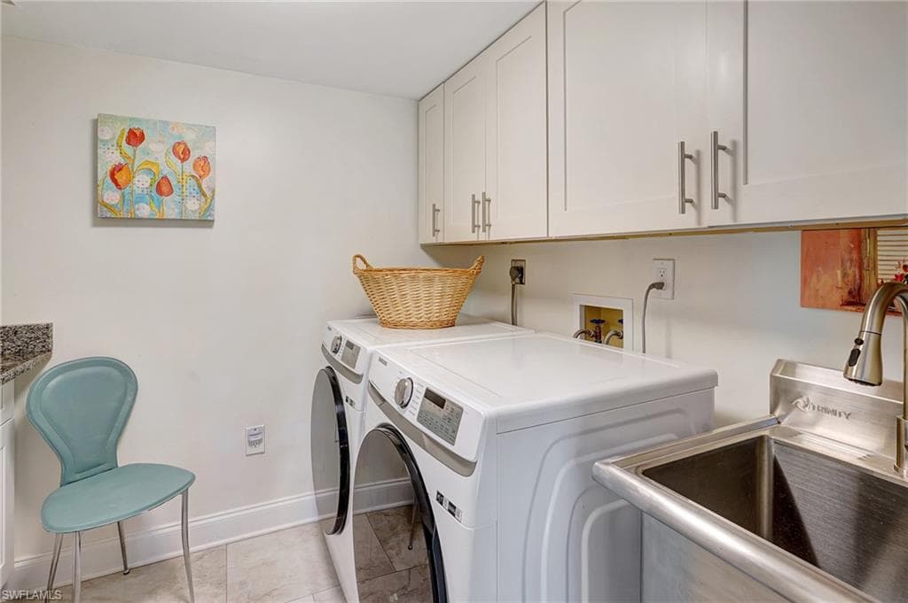 Laundry area featuring baseboards, a sink, washer and dryer, cabinet space, and light tile patterned floors