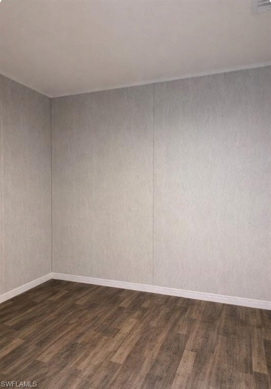 Empty room featuring dark wood-type flooring and baseboards