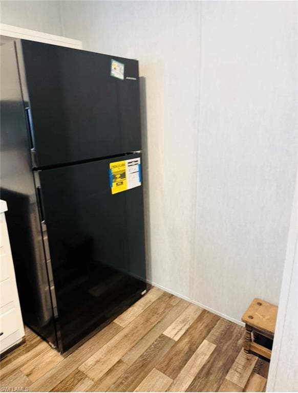 Kitchen view of freestanding refrigerator and light wood-style flooring