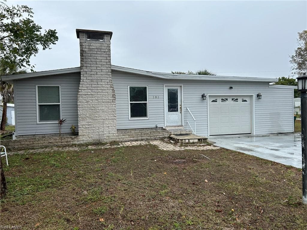 View of front of property featuring an attached garage, driveway, and a chimney