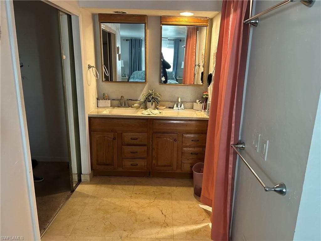 Full bathroom with double vanity and a shower stall
