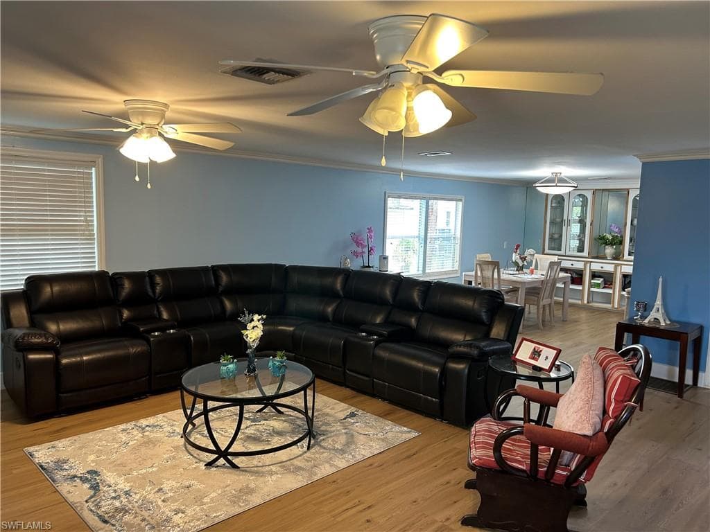 Living room with ornamental molding, vinyl finished floors, and ceiling fan
