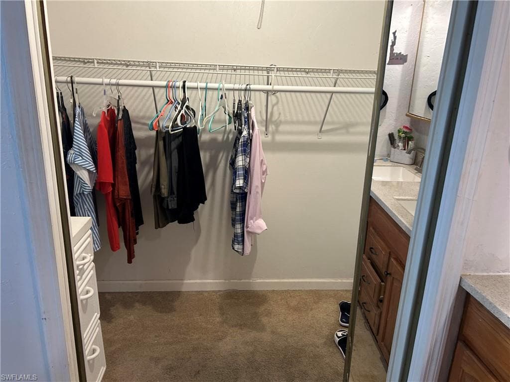 Walk in closet featuring a sink and dark colored carpet