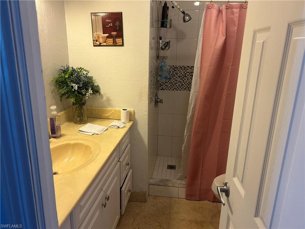 Full bath with vanity, a stall shower, and a textured wall