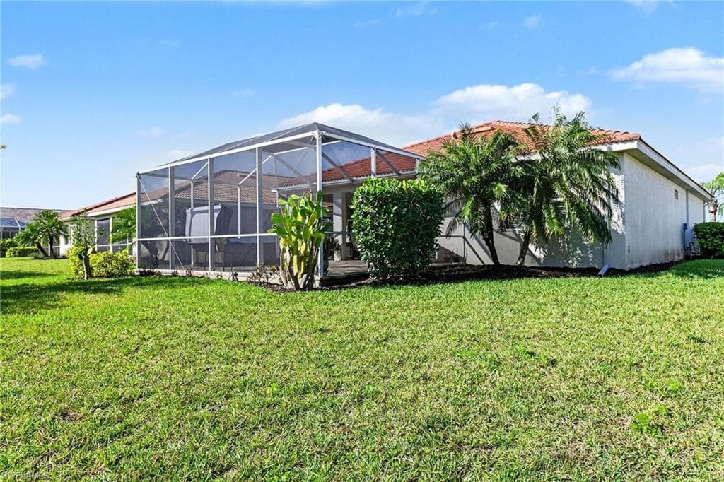 View of grassy yard with glass enclosure and a sunroom