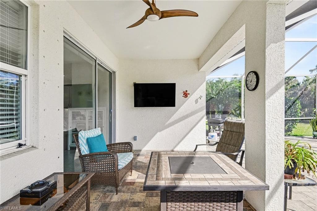 View of patio with ceiling fan, a lanai, and an outdoor fire pit