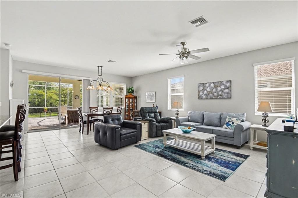 Living area with a ceiling fan, light tile patterned flooring, hanging lights, and healthy amount of natural light