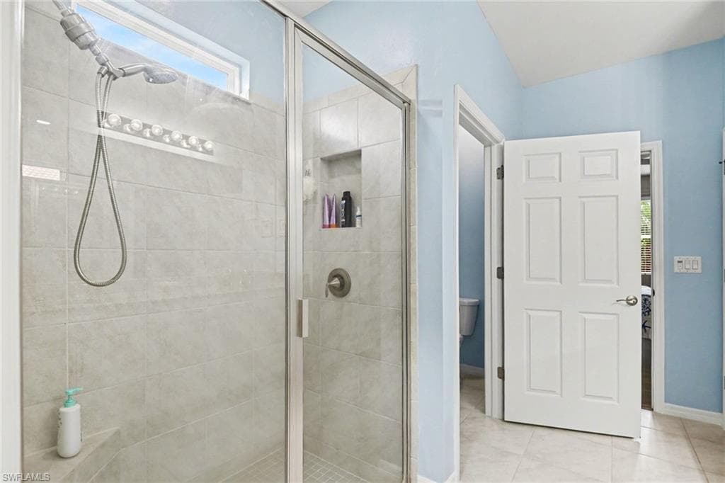 Bathroom with healthy amount of natural light, a shower stall, and light tile patterned floors