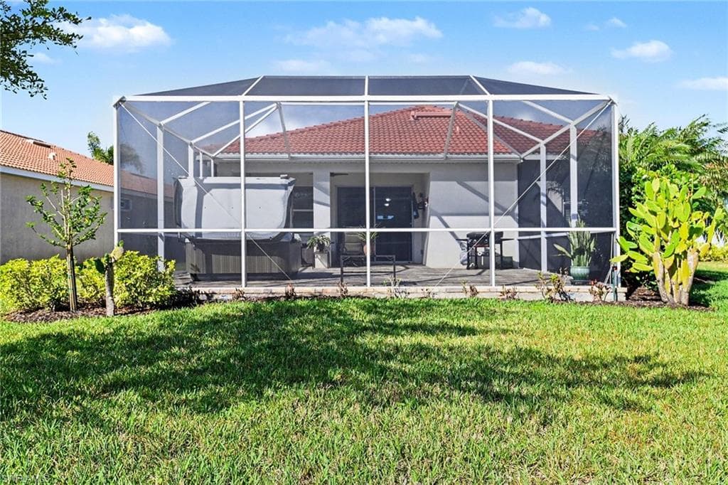 Rear view of property with a sunroom, a lanai, and a yard