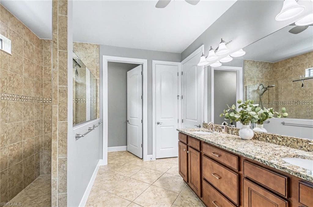 Bathroom with a walk in shower, double vanity, a ceiling fan, and light tile patterned floors