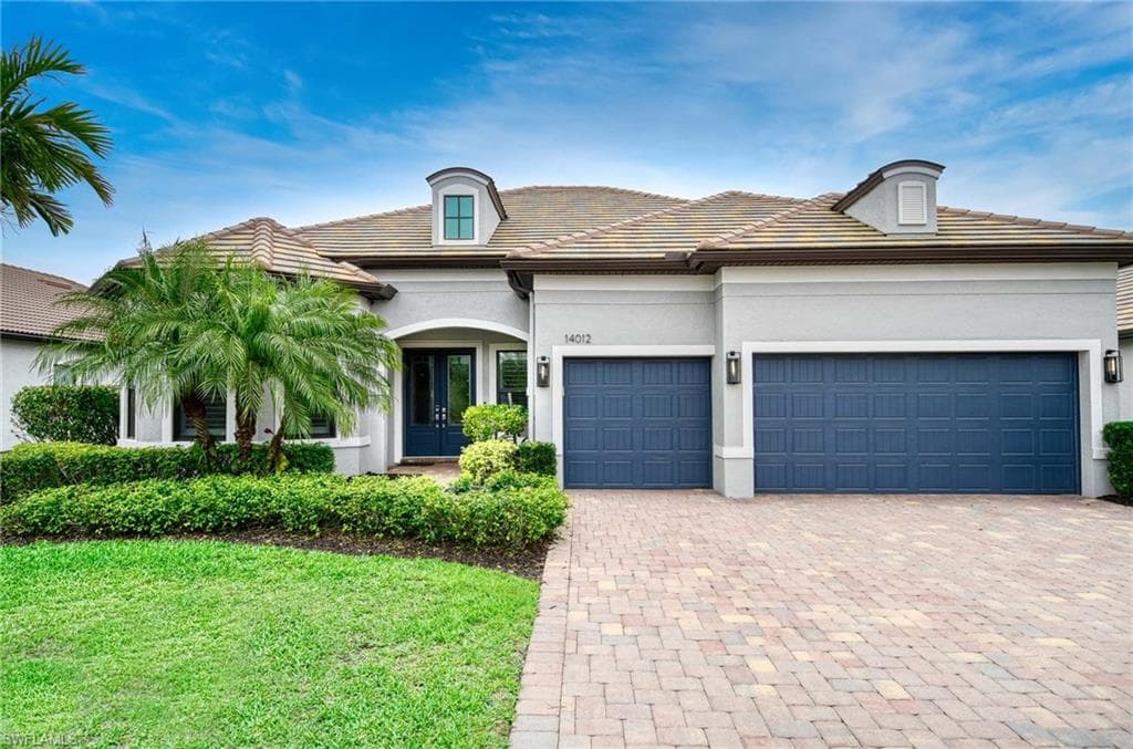 View of front of home with driveway, stucco siding, an attached garage, a tile roof, and french doors