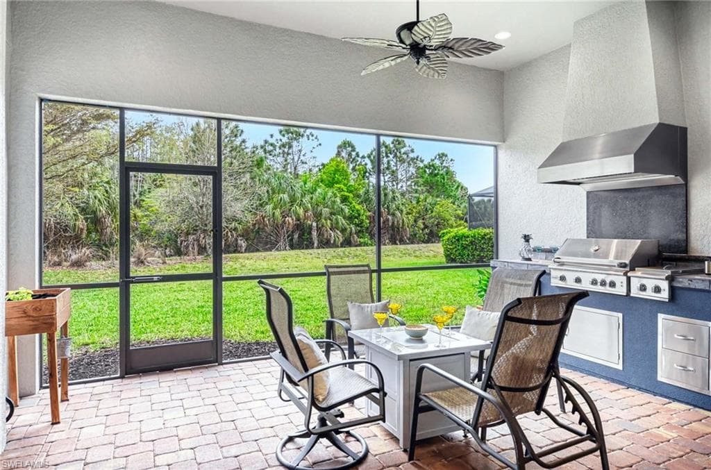 Sunroom / solarium featuring an outdoor kitchen / dining area, ceiling fan, and a patio