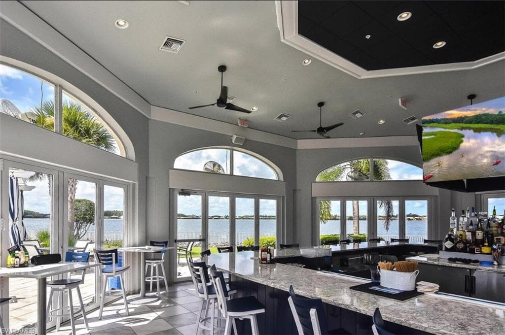 Kitchen with light stone countertops, a water view, a breakfast bar area, healthy amount of natural light, and recessed lighting