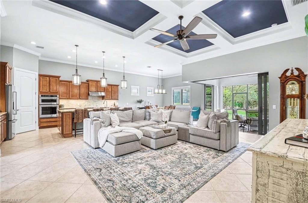 Living room featuring coffered ceiling, crown molding, ceiling fan, light tile patterned floors, and suspended lighting