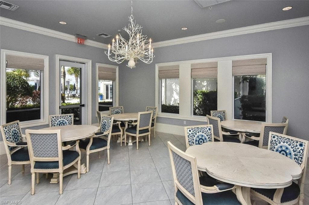 Dining area with light tile patterned flooring, a chandelier, and crown molding