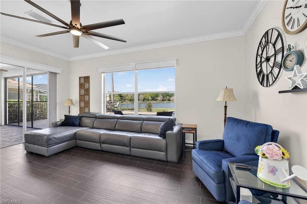 Living room featuring ornamental molding, a water view, wood finish floors, and a large ceiling fan.