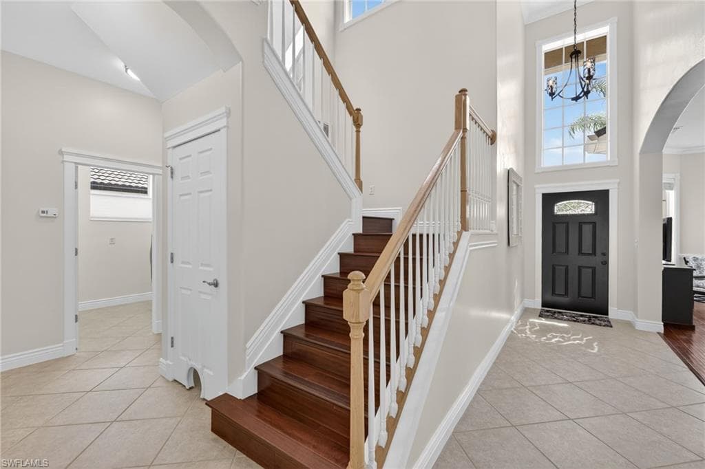 Foyer entrance with arched walkways, a high ceiling, a chandelier and ornamental molding