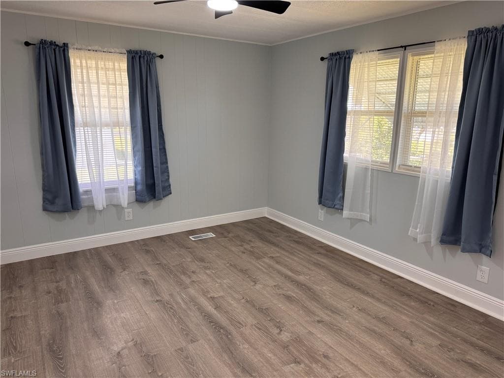 Master unfurnished bedroom featuring ceiling fan, laminate flooring, wide floor molding, window treatments