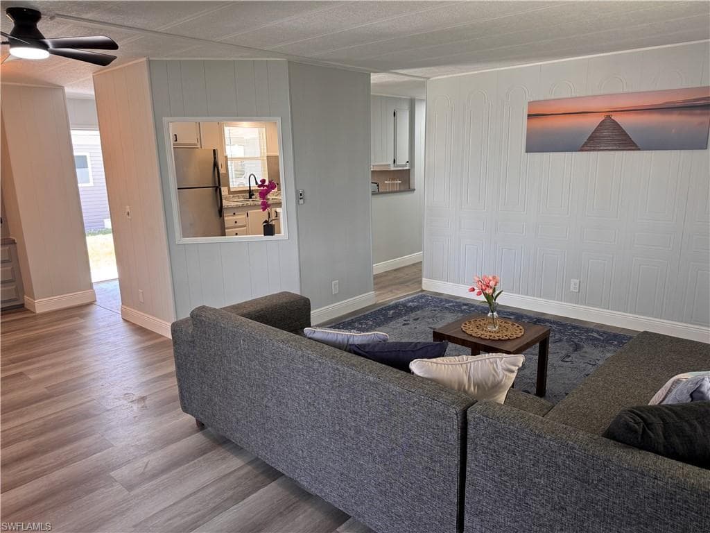 Living room view of kitchen and dining. Decorative accent wall, laminate flooring