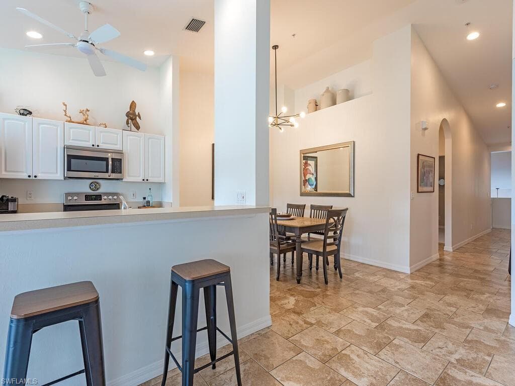 Kitchen featuring white cabinets, a ceiling fan, light countertops, stainless steel appliances, and arched walkways