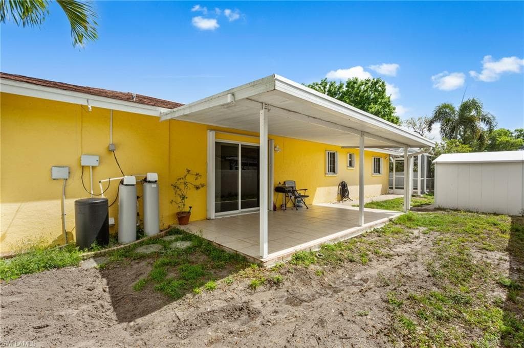 Back of house with stucco siding, a patio, and an outbuilding