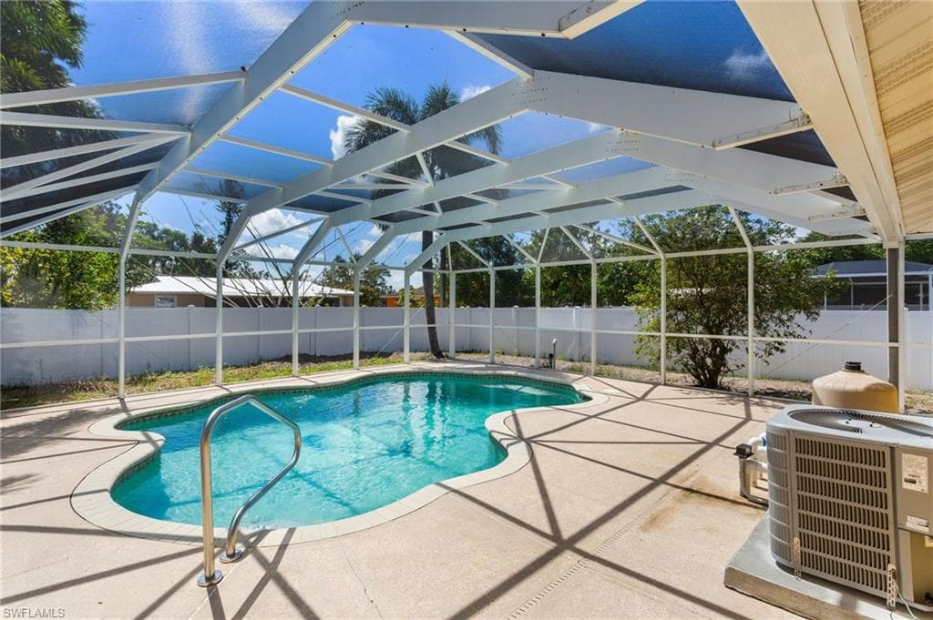 View of swimming pool with a fenced backyard, patio surround, and a screened pool cage.