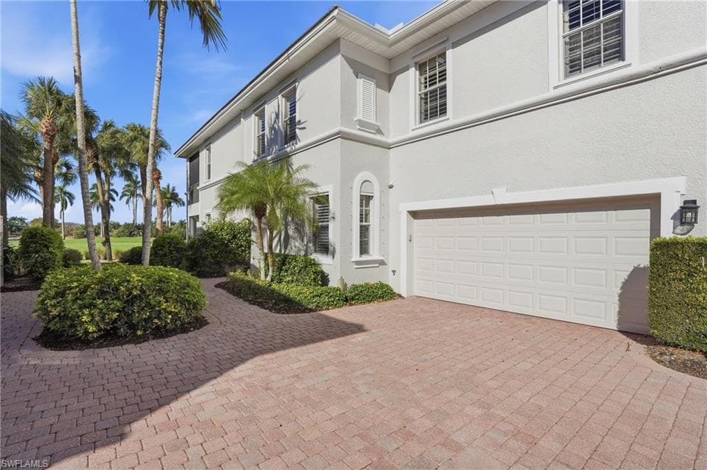 View of front facade with an attached garage, driveway, and stucco siding