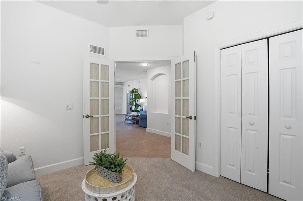 Sitting room with light carpet, arched walkways, and french doors