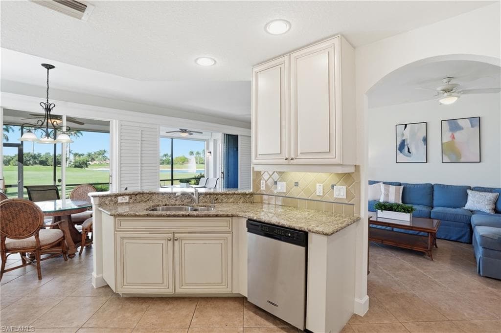 Kitchen with a ceiling fan, open floor plan, dishwasher, and light stone countertops